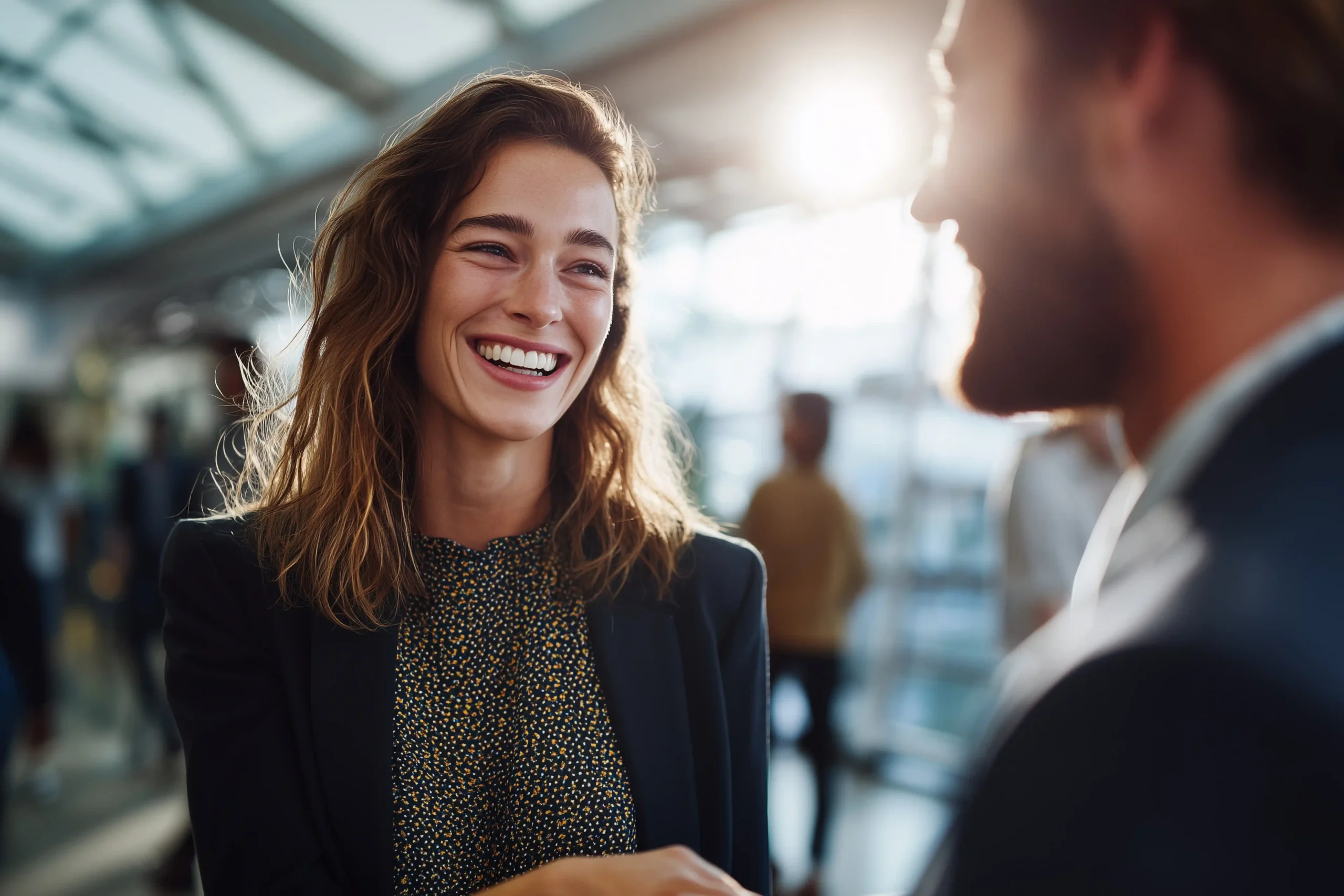 Smiling businesswoman engaged in a friendly conversation with a colleague in a professional setting.